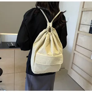 Detailed back view of a minimalist cream nylon drawstring backpack featuring a rear flap pocket