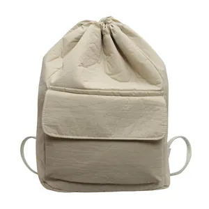 Detail showing the front pocket and drawstring closure of this beige nylon bucket backpack.