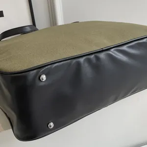 Nahaufnahme von armeegrünem Segeltuch und schwarzem Lederboden mit Metallfüßen an Tasche