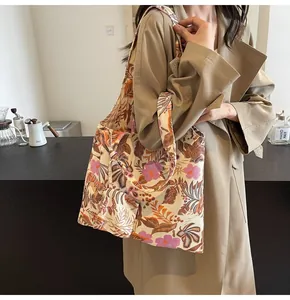 Detailed view of a floral printed canvas tote bag carried by a model in a cafe setting