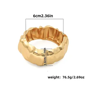 Close-up detail of a chunky gold metal bangle showing width, diameter and weight