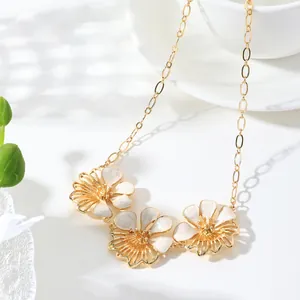 Detailed view of vintage gold enamel flower necklace with three white floral pendants.