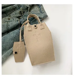 Beige felt coffin-shaped tote bag set with gothic cross embossing on denim background.