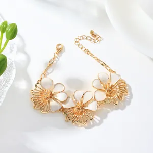 Close-up of elegant gold bracelet featuring white enamel flower charms and adjustable chain