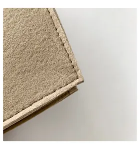 Macro view of the fine stitching and beige felt texture on a modern handbag edge