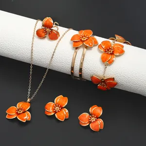 Close-up of a vibrant orange enamel flower jewelry set including necklace and earrings