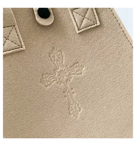 Macro detail of a beige felt handbag featuring an embossed ornate cross pattern