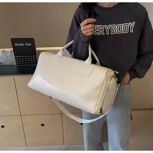 Bolsa de viaje y gimnasio crema de gran capacidad llevada por una persona con estilo
