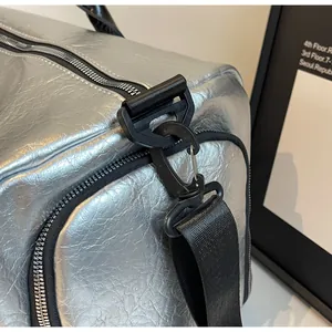 Primer plano del mosquetón negro y tela plateada texturizada en bolsa de viaje.