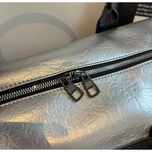Primer plano del detalle de la cremallera metálica doble en elegante bolsa de viaje plateada.