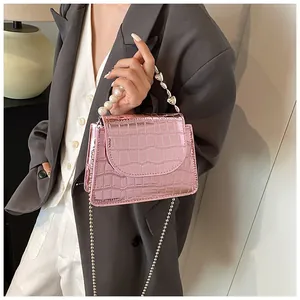 Vista dettagliata della borsa rosa metallizzato motivo coccodrillo con manico di perle