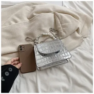 Mini borsa a mano argento coccodrillo con manico in perle e tracolla a catena.