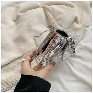 Primo piano di una mini borsa quadrata argento metallizzato con tracolla di perline.