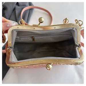 Detail van roze handtas met reliëf, chevron-voering en gouden kliksluiting zichtbaar.