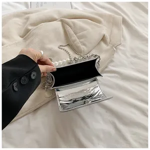 Dettaglio ravvicinato di mini borsa argento con catena di perle e cuori