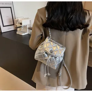 Détail d'un mini sac à dos matelassé argenté avec cordon et bandoulière chaîne.