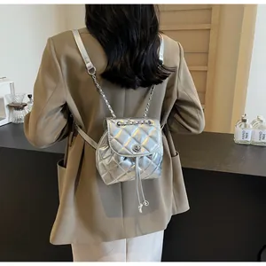 Vue de dos d'un sac à dos matelassé argenté porté sur un blazer beige très élégant
