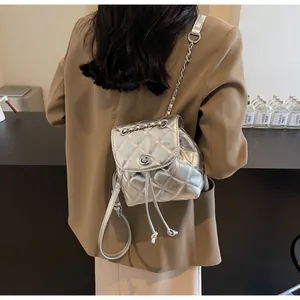 Petit sac à dos matelassé argenté moderne avec cordon de serrage porté par un mannequin mode
