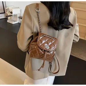 Sac seau matelassé marron brillant avec bandoulière chaîne porté par un mannequin