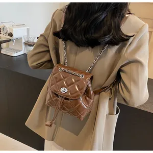 Vue détaillée du sac à dos en cuir verni matelassé marron avec bretelles chaîne.