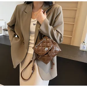 Vue détaillée d'un sac à dos seau matelassé brillant marron porté avec un blazer