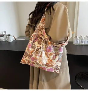 Large casual floral print canvas tote bag worn over the shoulder in a cafe setting