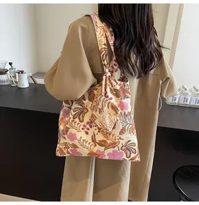Back view of a model carrying a floral print canvas tote bag in a cozy cafe setting