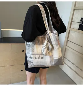 Lifestyle shot of large canvas tote bag with vintage newspaper print and matching pouch