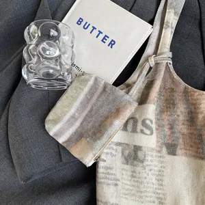 Vintage newspaper print canvas tote bag with matching pouch on casual suit background