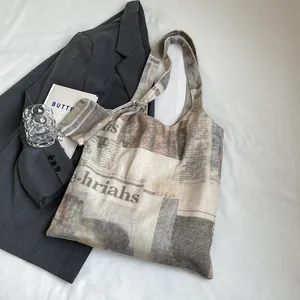 Detailed close-up view of large newspaper print canvas tote bag and matching pouch