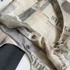 Close-up of canvas tote bag with newspaper print and secure magnetic snap closures.
