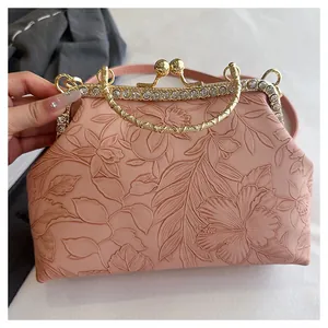 Detailweergave van roze clutch met bloemenreliëf en strass steentjes goud frame