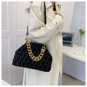 Elegante schwarze gesteppte Handtasche mit goldener Kette am Arm eines Models.