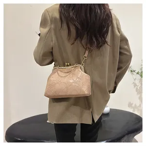 Detail van de beige handtas met bloemenreliëf, strass-frame en een kus-sluiting