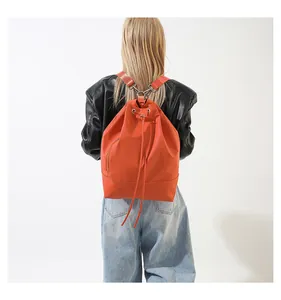 Detailansicht einer Frau mit einem stylischen orangefarbenen Tunnelzug-Rucksack.