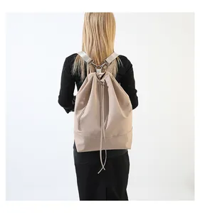 Rückansicht eines Models mit einem stilvollen beigen Kordelzug-Rucksack für Reisen.