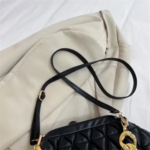 Nahaufnahme einer schicken schwarzen Stepptasche mit Goldkette und verstellbarem Riemen