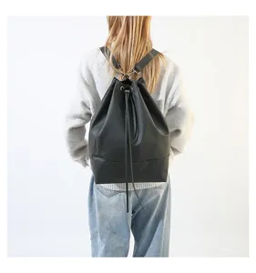 Rückansicht einer Frau mit einem großen schwarzen Kordelzug-Rucksack im minimalistischen Stil