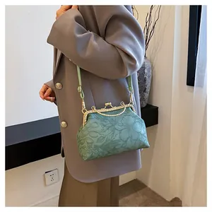 Detail van het elegante bloemreliëf en de strass sluiting van de groene handtas.