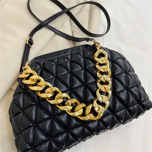 Detailansicht einer schwarzen Stepptasche mit markanter Goldkette und Schultergurt