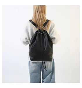 Weibliches Modell mit einem eleganten schwarzen Kordelzug-Rucksack für den Pendler-Look
