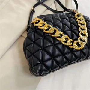 Nahaufnahme einer schwarzen Stepptasche mit einem modischen goldenen Kettengriff-Detail