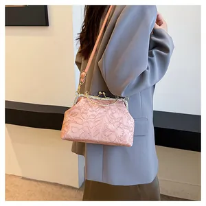 Zijaanzicht van roze handtas met reliëf en strass gedragen door model in grijze blazer
