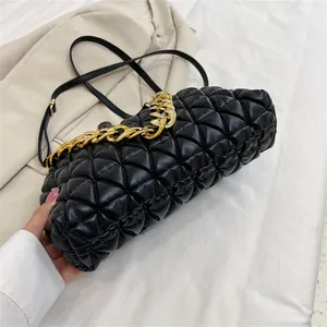 Detail der schwarzen gesteppten Clutch mit goldener Kette.