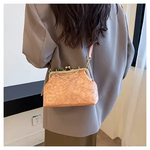 Detail van roze handtas met bloemreliëf en een elegante kliksluiting versierd met strass.