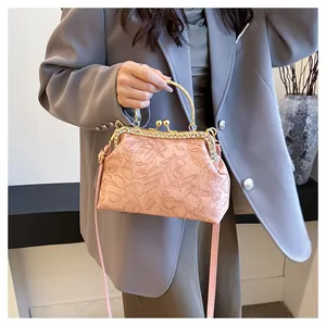 Detail van roze handtas met bloemreliëf, strass-beugelsluiting en goudkleurig handvat