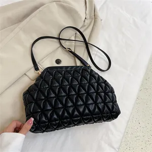 Detailansicht einer schwarzen gesteppten Tasche mit Dreiecksmuster und goldenem Verschluss.
