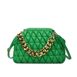 Detailansicht einer grünen Stepphandtasche mit klobiger goldener Kette und Rahmenverschluss