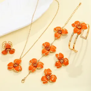 Detailed view of an orange enamel flower jewelry set including necklace, earrings and bracelet