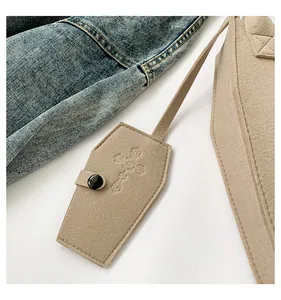 Close-up of a beige felt tote bag featuring a unique coffin-shaped cross pouch detail.